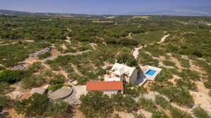 Una casa con techo rojo, piscina y vistas a un paisaje montañoso.