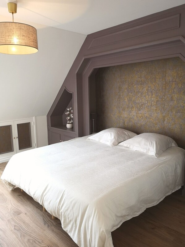 Ein Schlafzimmer mit einem großen Bett, einer hängenden Deckenleuchte und einer Wandverkleidung.