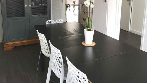 A dining area with a black table, white chairs, and a potted orchid.