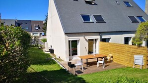 A modern house with a sloped roof, a wooden deck, and a fenced backyard.