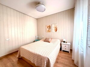 Un dormitorio con una cama, una mesita de noche, una silla y una lámpara en el techo.