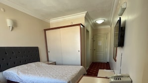 Una habitación de hotel con cama, escritorio, teléfono y espejo.
