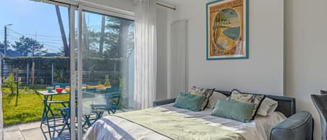 A bedroom with a large bed, a view of the outdoors, and a painting on the wall.