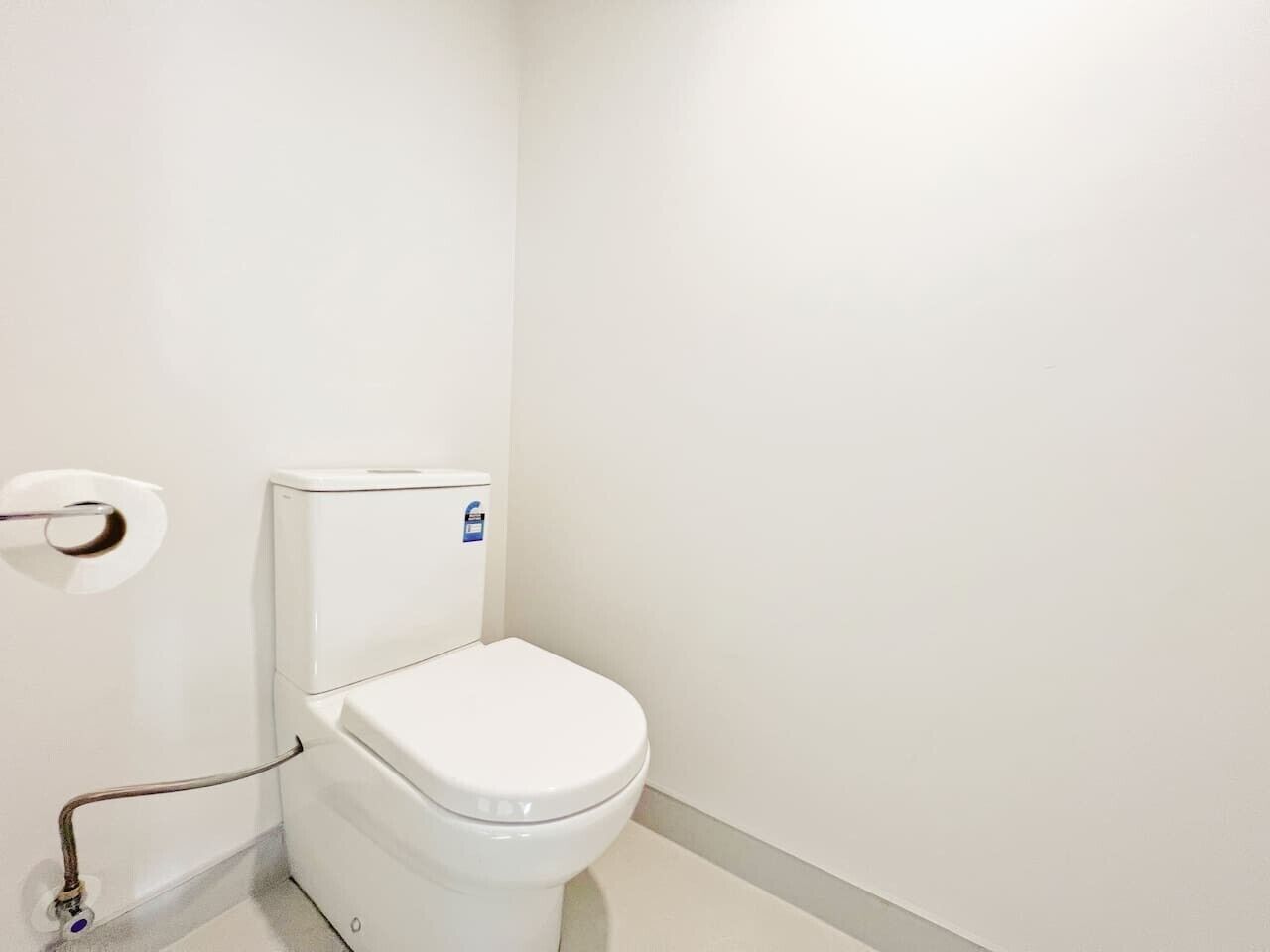 A white toilet with a flush handle and a blue sticker on the tank.