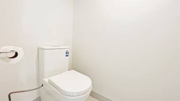 A white toilet with a flush handle and a blue sticker on the tank.
