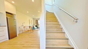 Una cocina moderna con refrigerador empotrado, piso de madera y una escalera con barandilla de metal.