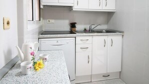 Una cocina moderna con armarios blancos, lavavajillas y encimera de granito.