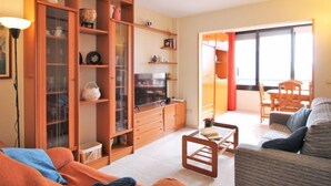 Una sala de estar con un sofá, una mesa de centro y una unidad de estanterías de madera con puertas de vidrio.