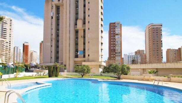 Una piscina con vistas a edificios residenciales altos al fondo.