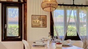 Een eetgedeelte met een tafel voor vier personen, een hanglamp en een raam met gordijnen.