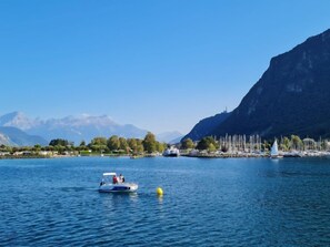 A lake with a boat, a sailboat, and a mountain in the background. - Dorenavant by Interhome (Le Bouveret)