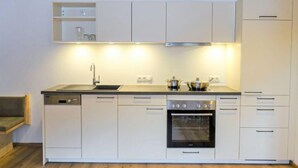 A modern kitchen with white cabinets, a black sink, a stove, and an oven. - Freiheit-La by Interhome (Pettneu am Arlberg)