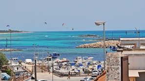 Un puerto deportivo con barcos, un rompeolas rocoso y un mar azul cristalino.