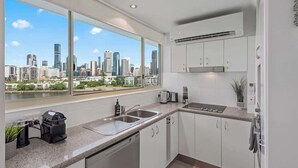 Una cocina moderna con vistas a la ciudad, armarios blancos y un ventanal grande.