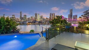 Una piscina en la azotea con un horizonte urbano y un puente al fondo.