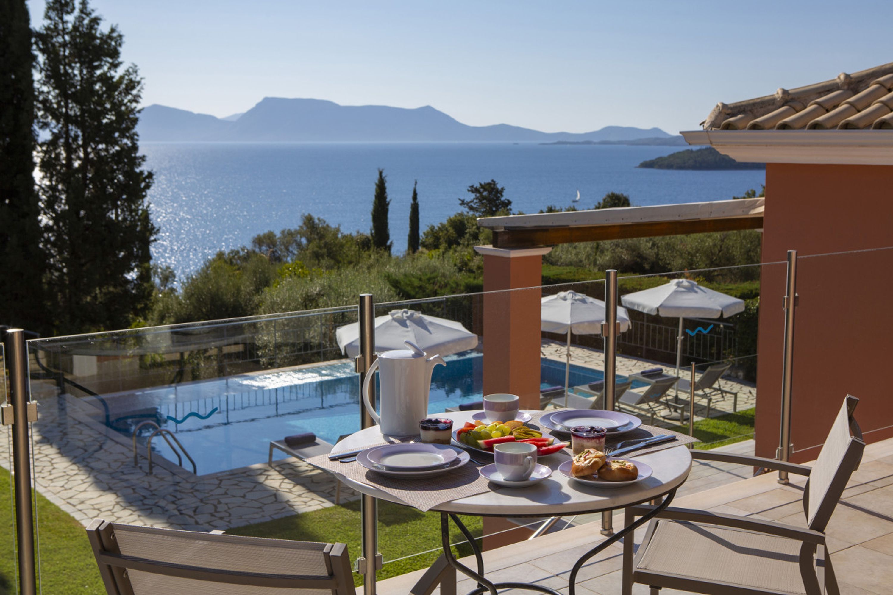 A poolside dining area with a view of the sea and mountains.