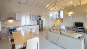 Eine moderne Küche mit Essbereich, einer Couch und einem Fernseher im Wohnzimmer.