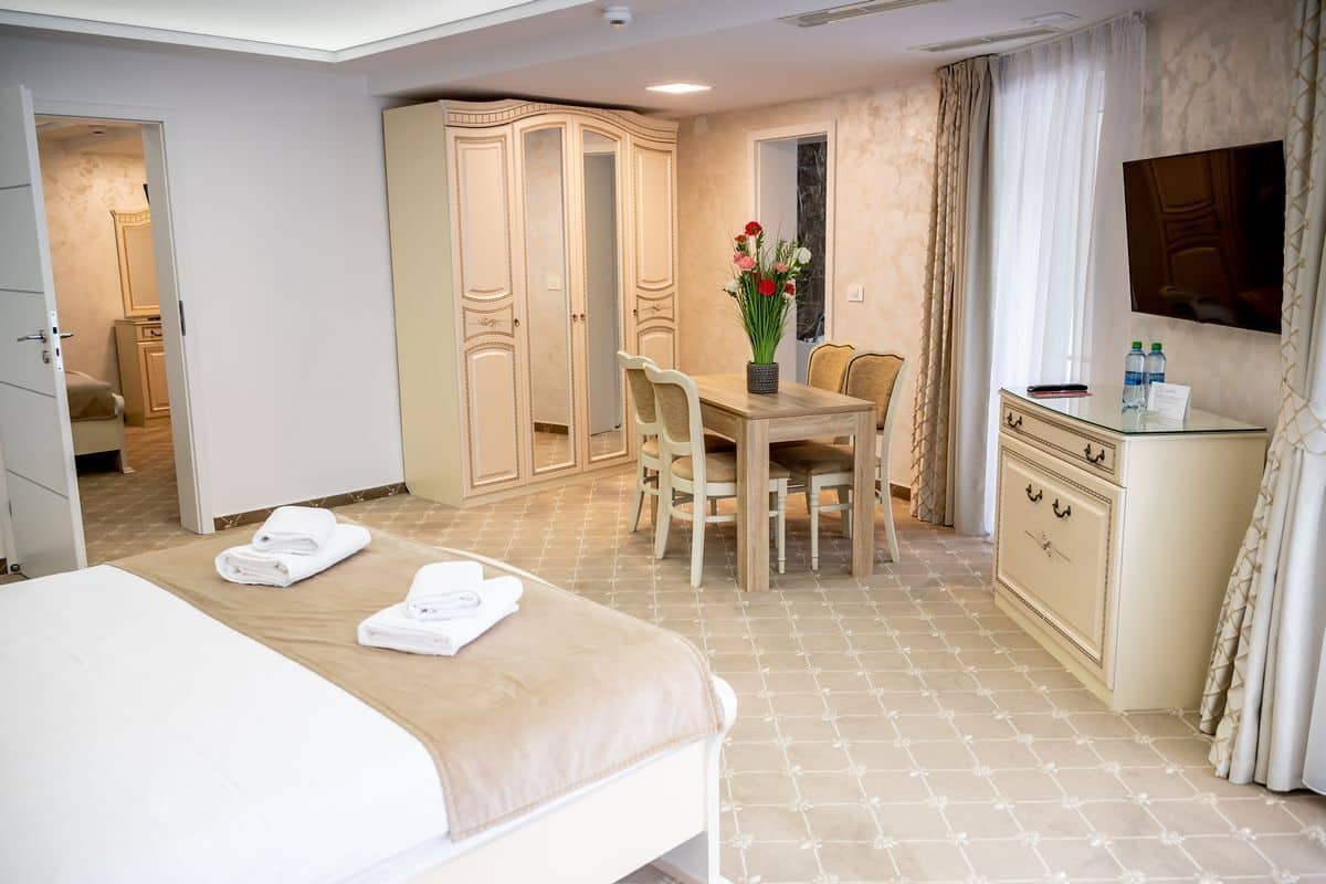 Une chambre d’hôtel comprenant un lit, une table à manger avec des chaises, un téléviseur et une armoire.