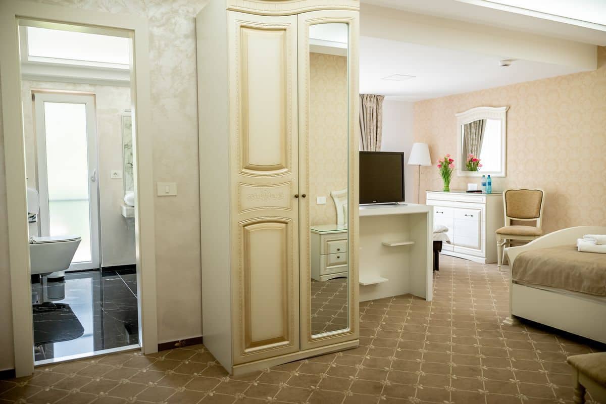 Une chambre d’hôtel équipée d’un placard, d’un bureau, d’une chaise, d’un lit, d’une télévision et d’une salle de bain.