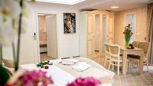 Una habitación de hotel con cama, una mesa de comedor con sillas, un armario y un cuadro en la pared.