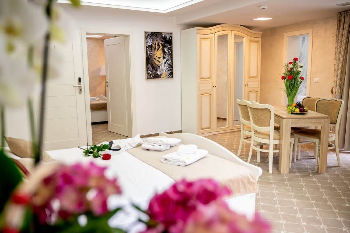 Une chambre d’hôtel avec un lit, une table à manger et des chaises, une armoire et un tableau au mur.