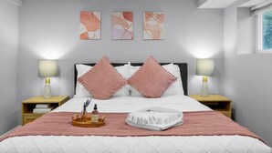 Une chambre moderne avec un grand lit, deux tables de chevet et trois œuvres d’art abstraites accrochées au mur.