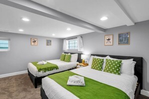 Hotellihuone, jossa on kaksi sänkyä, ikkuna ja kattoon upotetut valaisimet.