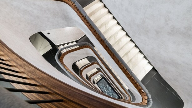 A spiral staircase with a wooden handrail and a view of the lower levels. - Elegant Apartment in the Center | Air Conditioning, Parking (Gdynia)