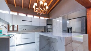 A modern kitchen with marble countertops, a built-in stove, and a stainless steel refrigerator. - 4BR Villa Heated Pool Private Nightclub-El Poblado (Medellín)