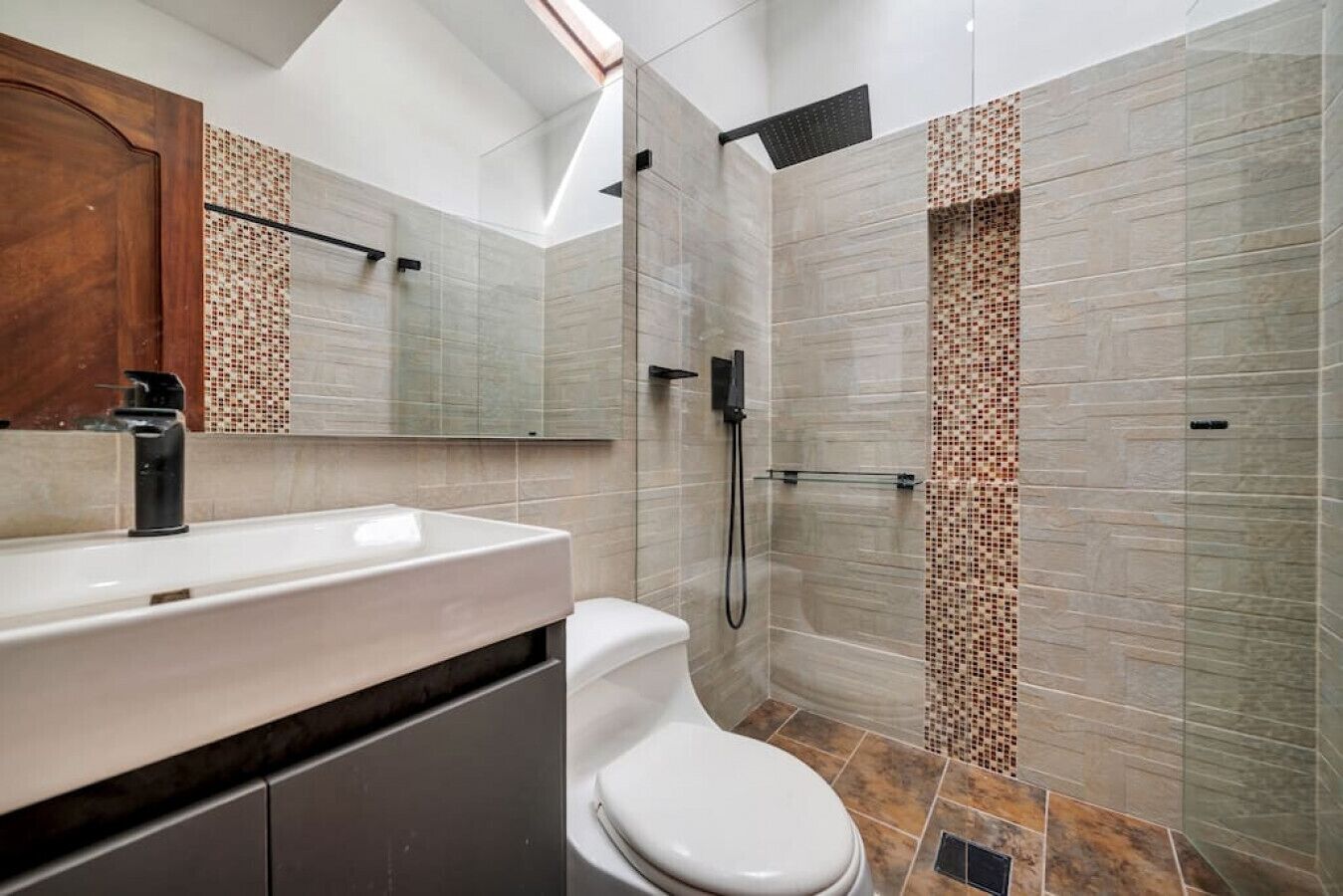 Un baño moderno con un espejo grande, un lavabo blanco y una zona de ducha.