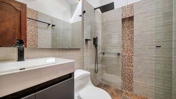 Un baño moderno con un espejo grande, un lavabo blanco y una zona de ducha.