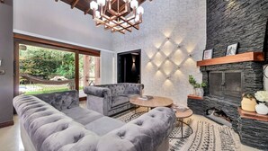 A modern living room with a grey sofa, a round coffee table, and a fireplace. - 4BR Villa Heated Pool Private Nightclub-El Poblado (Medellín)
