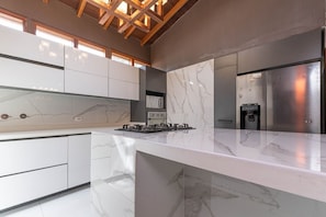 Una cocina moderna con encimeras de mármol, electrodomésticos de acero inoxidable y una estructura de techo de madera.