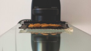 Une machine à café dotée d’un réservoir d’eau transparent et d’un bac d’égouttement en métal.