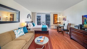 A hotel room with a bed, a sofa, a desk, and a dining area.