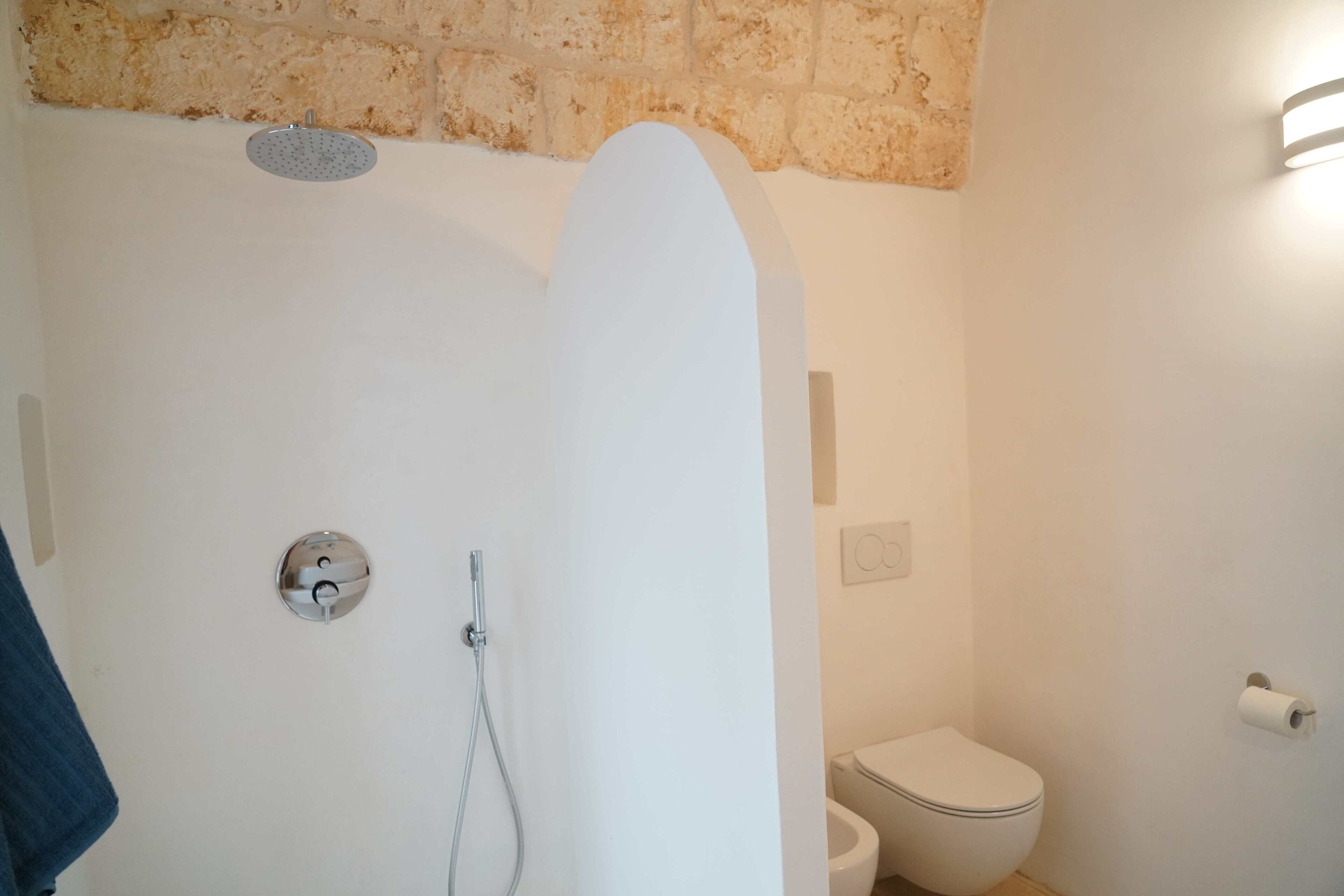 A bathroom with a shower, toilet, and a towel rack.
