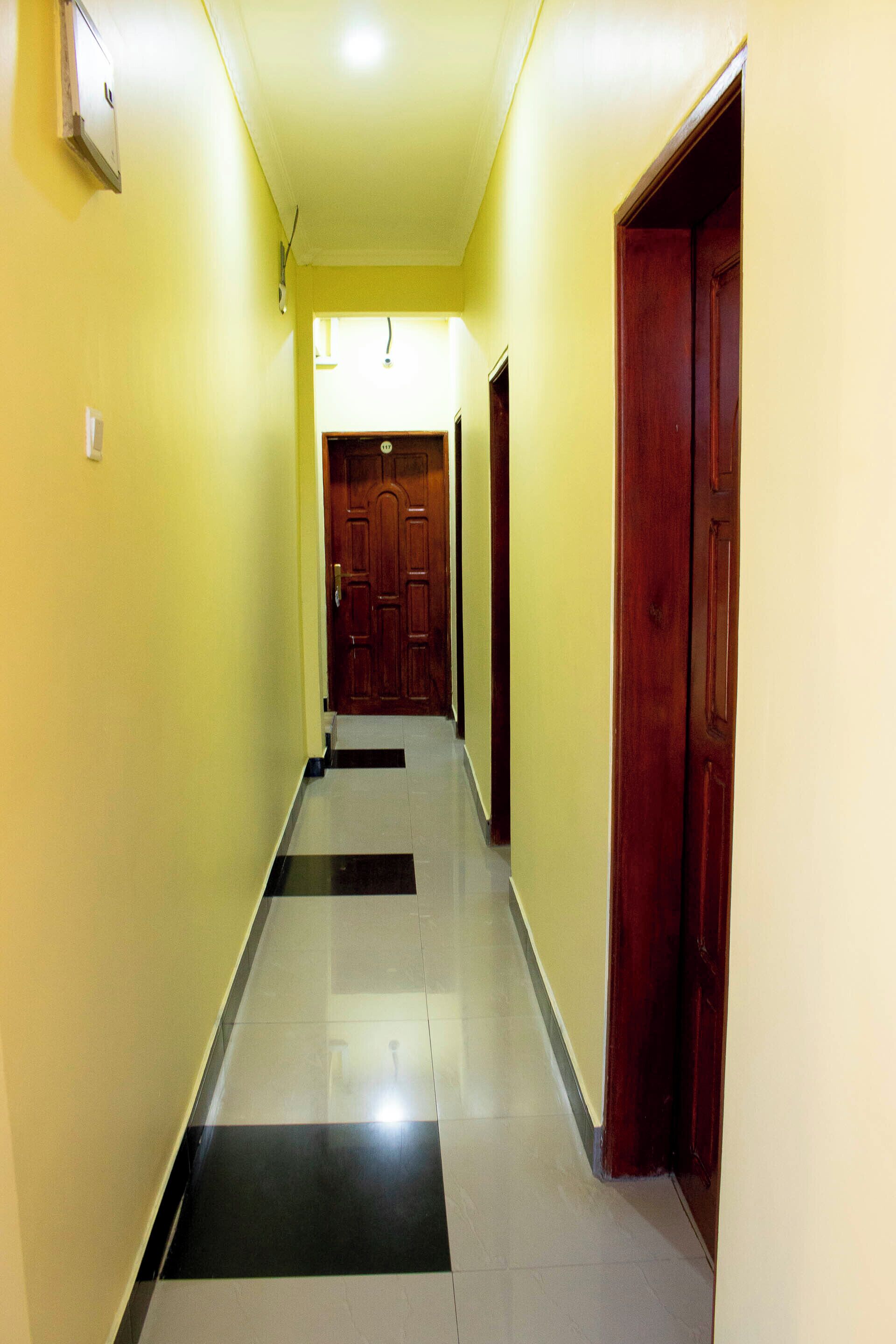 A hallway with yellow walls and a black and white tiled floor.