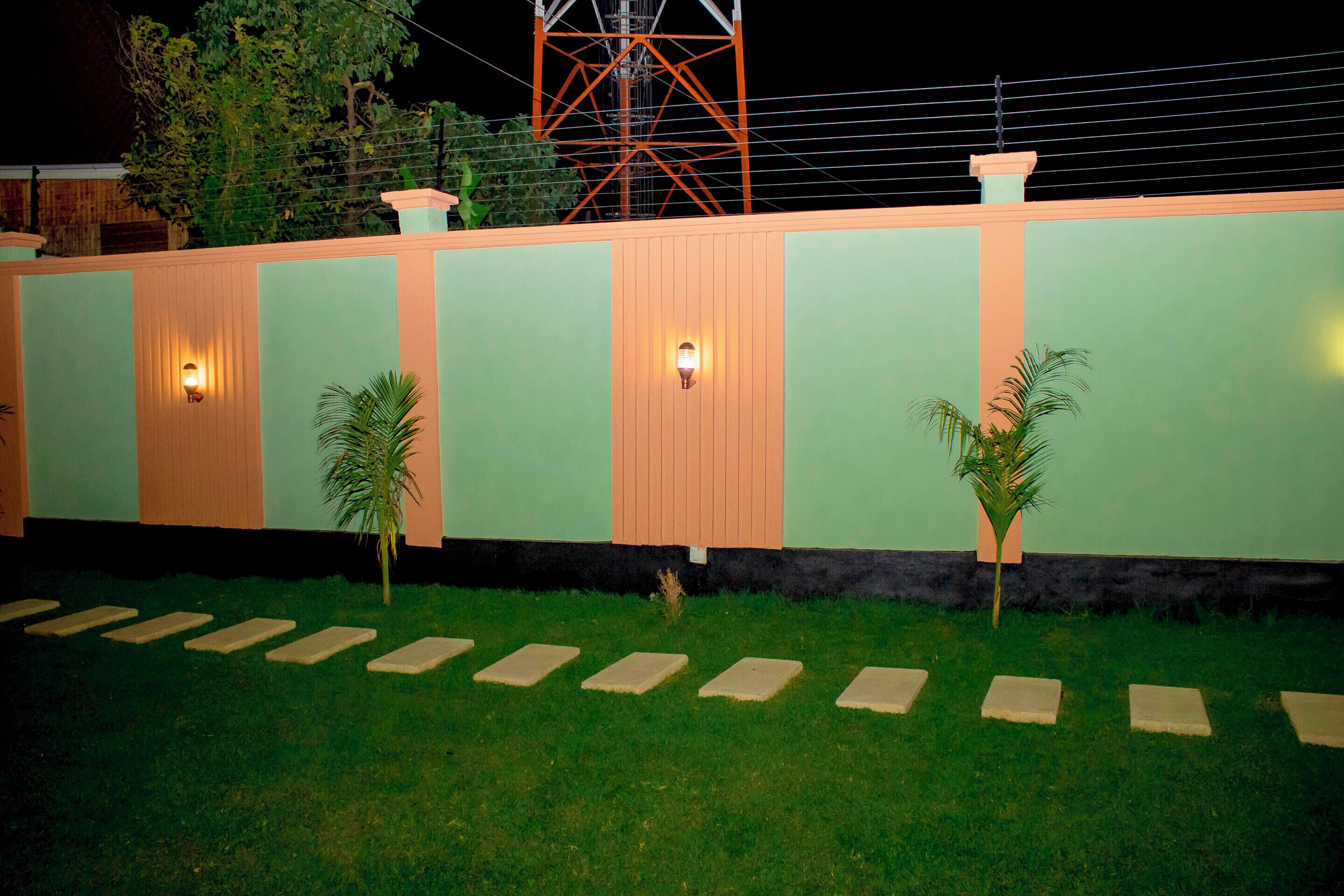 A building with a light green exterior, orange accents, and two small palm trees.