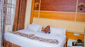 Una habitación de hotel con una cama, una mesita de noche y un cabecero de madera.