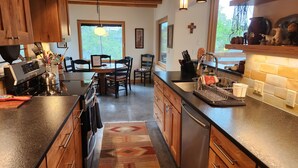 A modern kitchen with wooden cabinets, a stainless steel stove, and a dining area with chairs and a table.