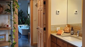 A bathroom with wooden cabinets, a sink, a mirror, and a shower area.