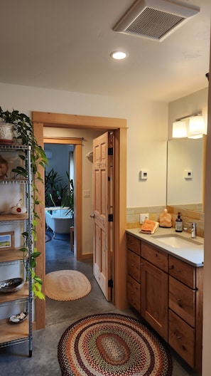 A bathroom with wooden cabinets, a sink, a mirror, and a shower area.