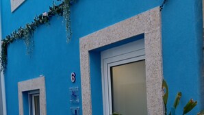 A blue building with a white door, a small window, and a number '6' sign. - Casa Típica no Centro do Porto (PORTO)