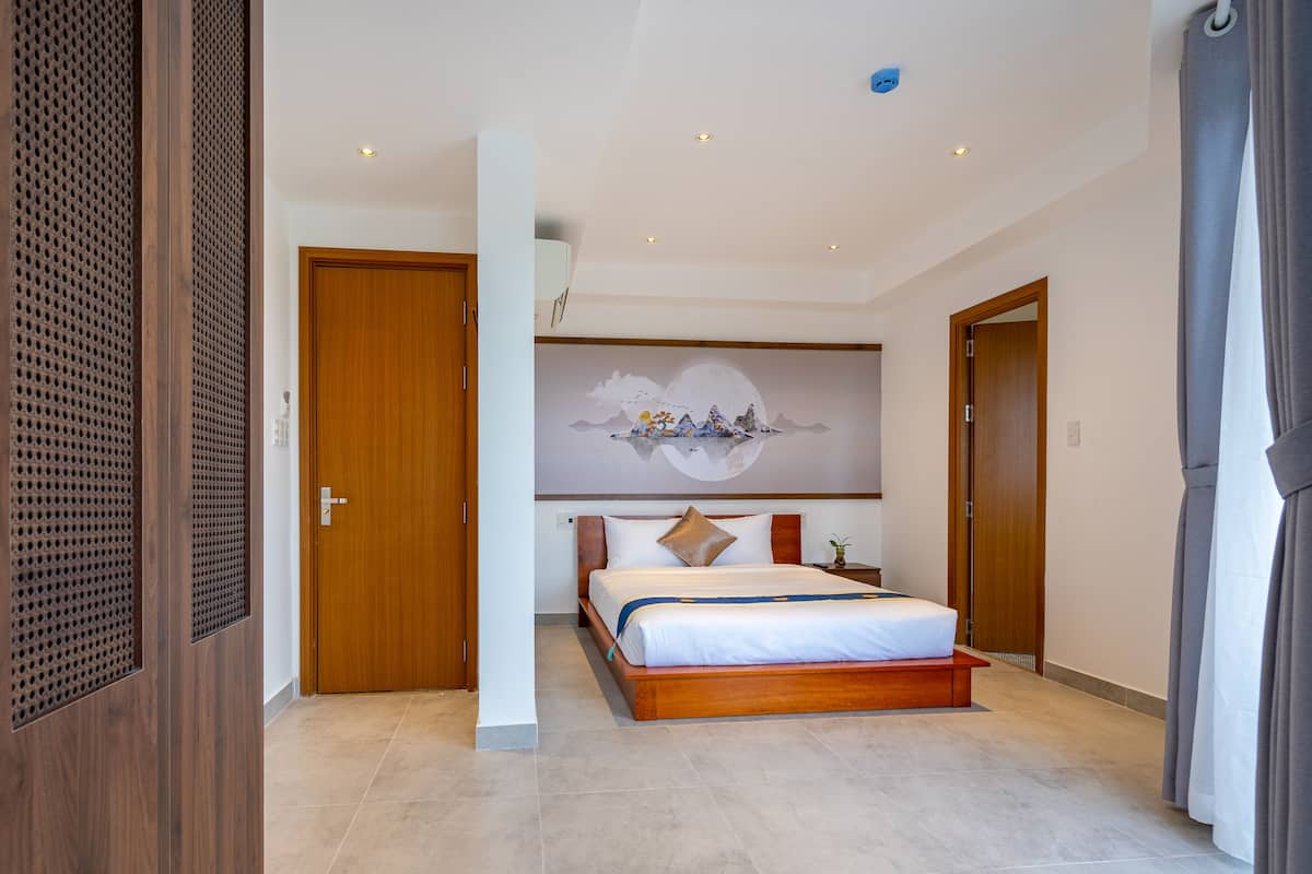A modern bedroom with a large bed, wooden doors, and a wall-mounted artwork.