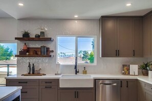 A modern kitchen with a large window, built-in cabinets, and a stainless steel dishwasher.