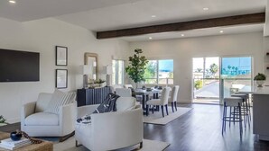 Un salón espacioso con una mesa de comedor y sillas, un sofá y una zona de cocina con barra.