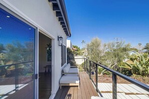 Un edificio moderno con terraza de madera, zona de estar techada al aire libre y vistas del paisaje circundante.