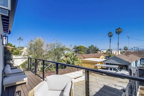Un balcon donnant sur un quartier résidentiel, avec des maisons et des palmiers.