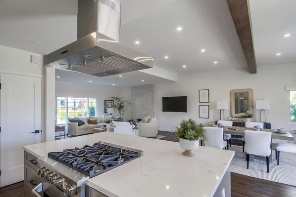 Una cocina moderna con una isla central, horno empotrado y campana extractora de acero inoxidable.