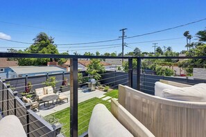 A rooftop patio with outdoor furniture, a view of the neighborhood, and a clear sky.